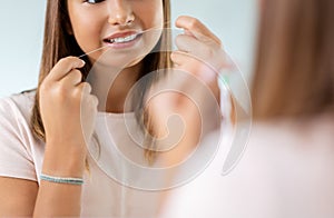 teenage girl with floss cleaning teeth at bathroom