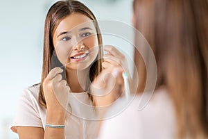 teenage girl with floss cleaning teeth at bathroom