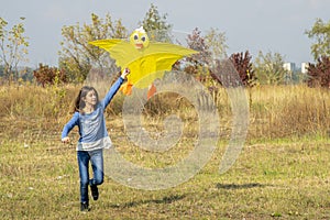 Teenage girl flying a yellow kite. Beautiful young girl kite fly. Happy little girl running with kite in hands on the beautiful