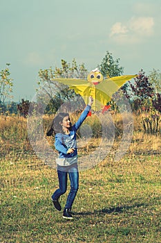 Teenage girl flying a yellow kite. Beautiful young girl kite fly. Happy little girl running with kite in hands on the beautiful