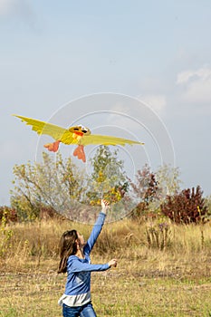 Teenage girl flying a yellow kite. Beautiful young girl kite fly. Happy little girl running with kite in hands on the beautiful