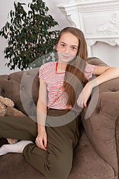 Teenage girl with freckles sit on her favorite cozy sofa