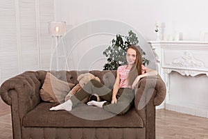 Teenage girl with freckles sit on her favorite cozy sofa