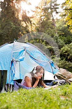 Teenage girl in front of tent camping in forest.