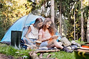 Teenage girl in front of tent camping in forest.