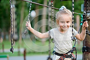 Teenage girl goes on hinged trail in rope park.