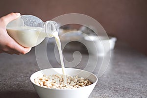 Teenage girl hands pour milk from plastic bottle