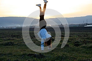 Teenage girl Handstanding on a field in late winter afternoon