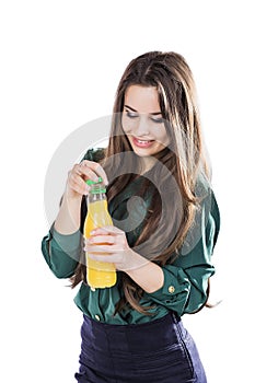 Teenage girl happy while holding a bottle of orange juice.in a green blouse. isolated on a white background.opens a bottle