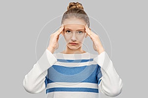 Teenage girl having headache over grey background