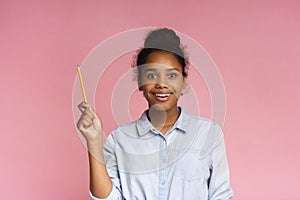 Teenage girl having idea, raising pencil in funny attention gesture