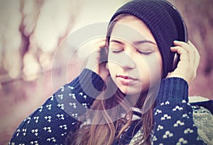 Teenage girl in headphones listens to music with closed eyes