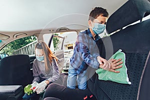 Teenage girl and her brothers cleaning the car with mask