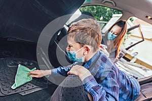 Teenage girl and her brothers cleaning the car with mask