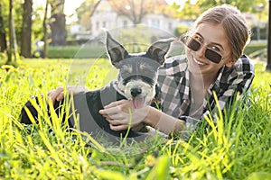 Teenage girl with her cute dog resting on green grass in park