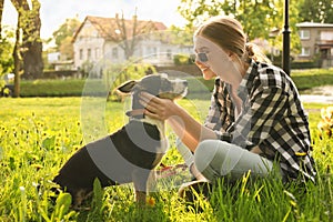 Teenage girl with her cute dog resting on green grass in park