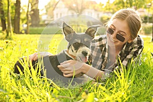 Teenage girl with her cute dog resting on green grass in park