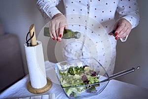 a teenage girl and her mother in pajamas are cooking and eating a fresh green and tomato salad together