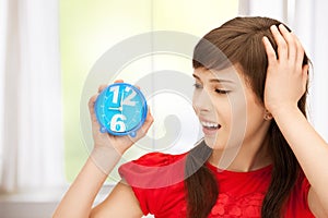 Teenage girl holding alarm clock