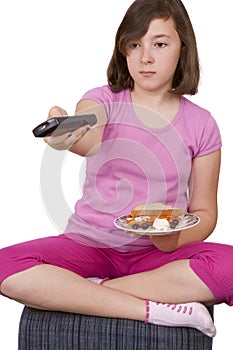 Teenage girl holding a plate with food and tv remote control