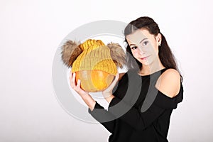 Teenage girl holding pumpkin in yellow cap with bobbles