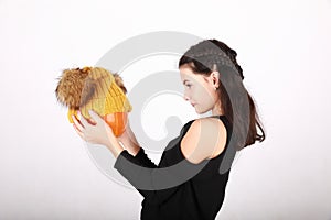 Teenage girl holding pumpkin in yellow cap with bobbles