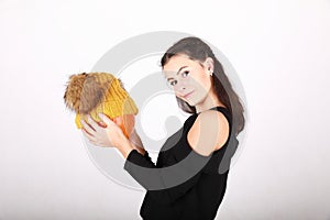 Teenage girl holding pumpkin in yellow cap with bobbles