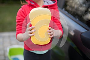 Teenage girl holding a sponge on a sunny day