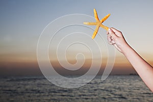 Teenage girl holding starfish, close up on human arm