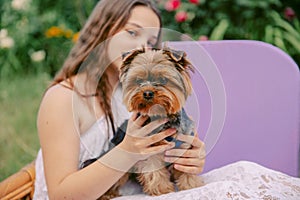 A teenage girl is holding a Yorkshire Terrier dog. Focus on the dog