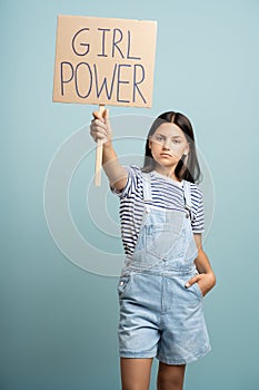 Teenage girl holds banner girl power. Young feministic woman protest against misogynistic society