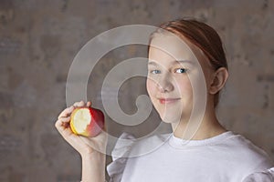 A teenage girl holds a bitten-off Apple in her hand. The concept of proper nutrition, healthy food, health, diet, fruit