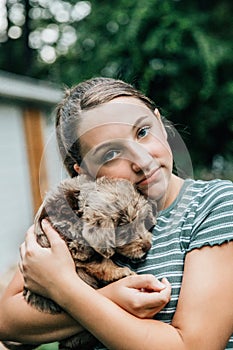 Teenage girl holds and snuggles with new labradoodle puppies photo