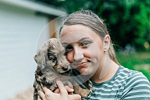 Teenage girl holds and snuggles with new labradoodle puppies photo