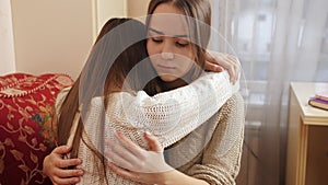 Teenage girl hugging and consoling her crying friend at bedroom. Friends support and teenager depression