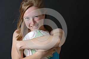 Teenage girl hugging a soccer ball