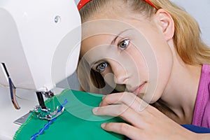 A teenage girl is interested in the process of sewing on the sewing machine