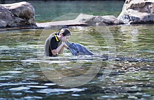 Teenage girl kissing a dolphin in an ocean lagoon