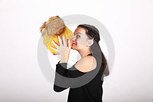 Teenage girl kissing pumpkin in yellow cap with bobbles