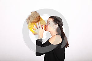 Teenage girl kissing pumpkin in yellow cap with bobbles