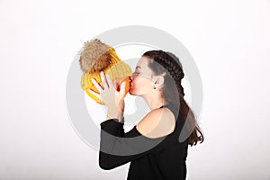 Teenage girl kissing pumpkin in yellow cap with bobbles