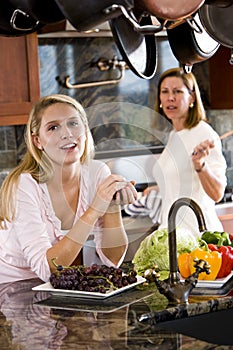 Teenage girl in kitchen chatting with mother