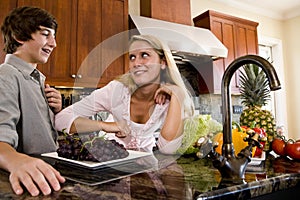 Teenage girl in kitchen talking with brother