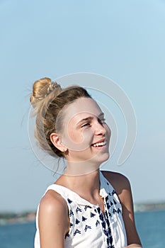 A teenage girl laughs contagiously against the backdrop of the sea coast.