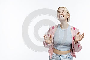 Teenage girl laughs. A cute blonde with freckles on her face in a blue top, jeans and a pink jacket. Positive and optimistic.