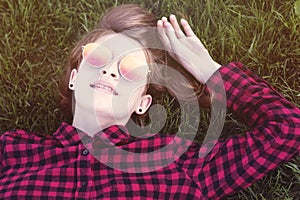Teenage girl laying on grass in park in sunglasses