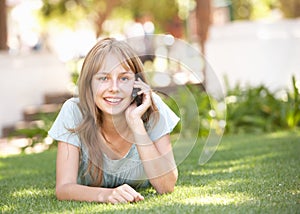 Teenage Girl Laying In Park Using Mobile Phone