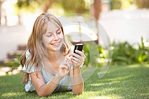 Teenage Girl Laying In Park Using Mobile Phone