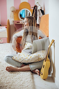 A teenage girl is learning to play the guitar, ukulele.