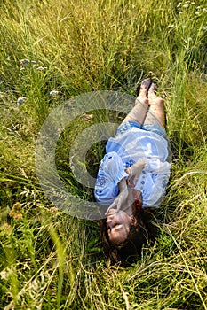 A teenage girl lies in a tall meadow grass